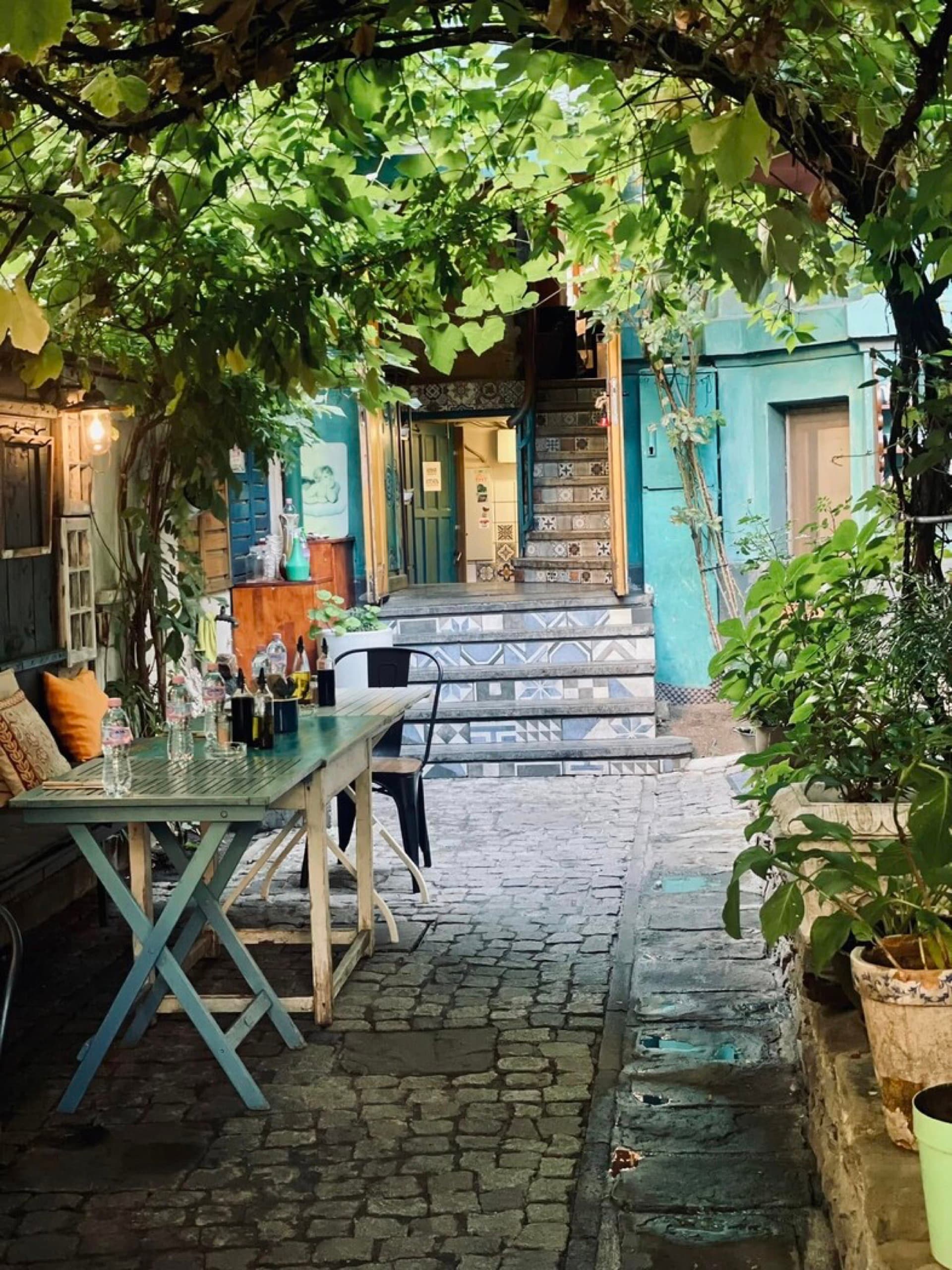 Vine-covered courtyard entrance with cobblestones and tiled steps